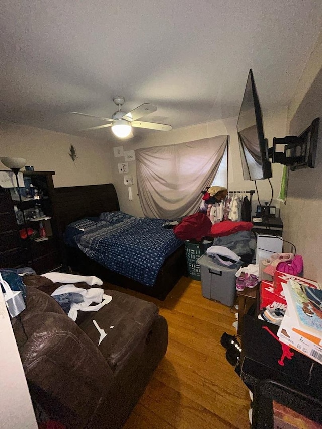 bedroom featuring ceiling fan, hardwood / wood-style floors, and a textured ceiling