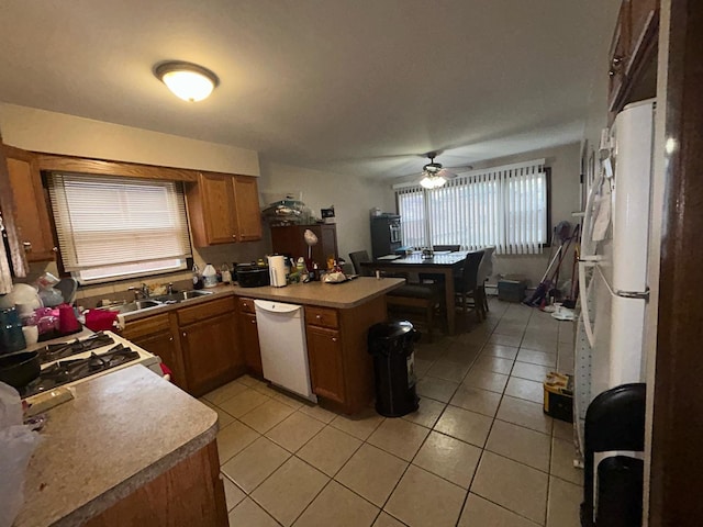 kitchen with sink, light tile patterned floors, ceiling fan, kitchen peninsula, and white appliances