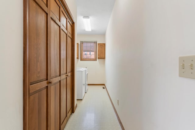 corridor featuring light floors, baseboards, and washing machine and clothes dryer