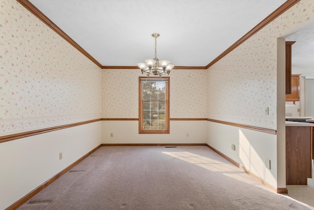 empty room featuring ornamental molding, a chandelier, light colored carpet, and wallpapered walls