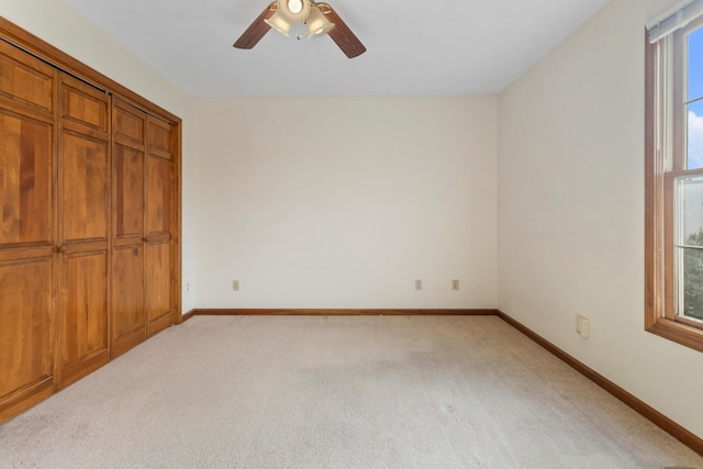 unfurnished bedroom with baseboards, a closet, a ceiling fan, and light colored carpet