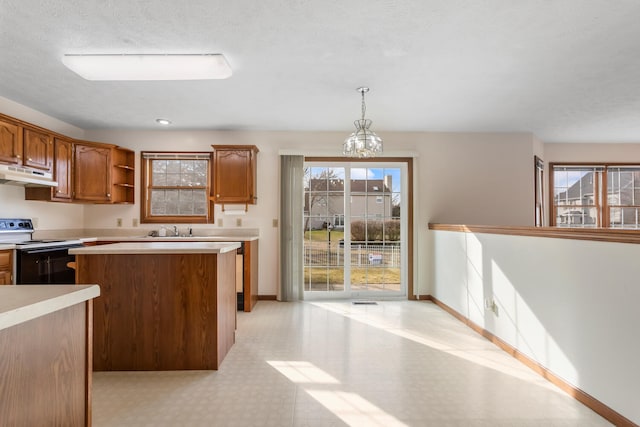 kitchen featuring light countertops, range with electric stovetop, decorative light fixtures, and under cabinet range hood