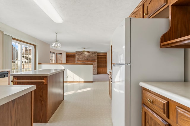 kitchen with pendant lighting, light floors, light countertops, brown cabinetry, and freestanding refrigerator