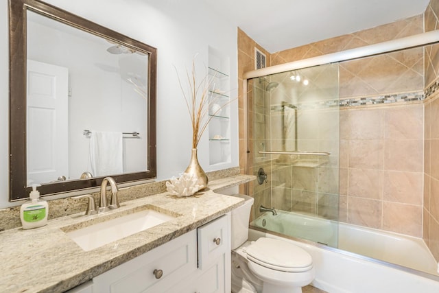 full bathroom with vanity, shower / bath combination with glass door, and toilet