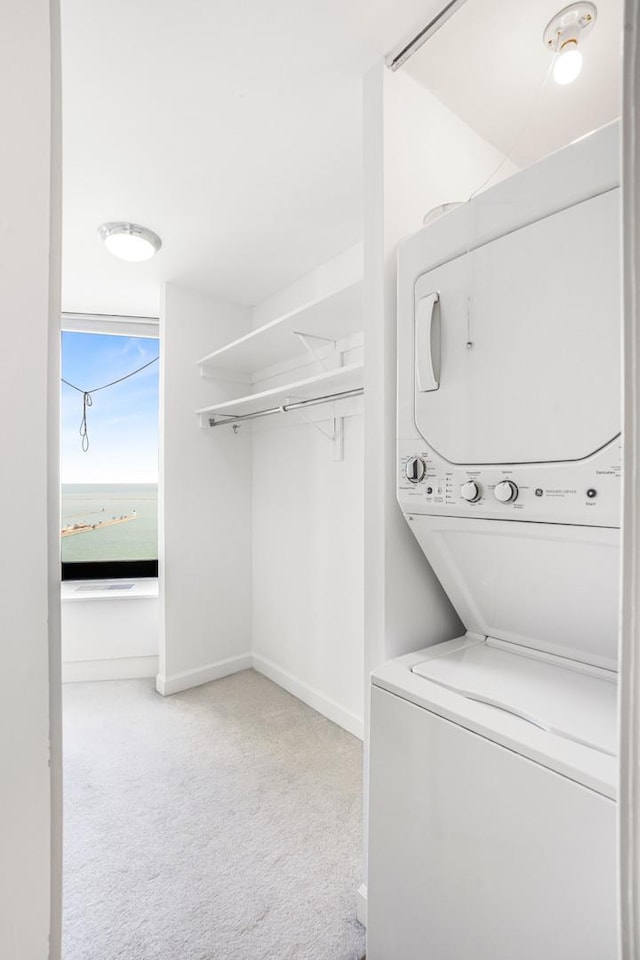 laundry room featuring light carpet and stacked washer and clothes dryer