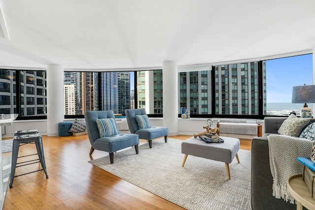 living room with expansive windows, wood-type flooring, a water view, and a wall unit AC