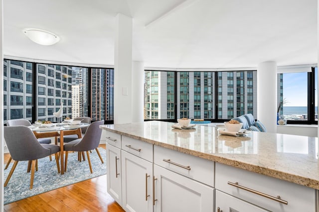 kitchen with white cabinets, light stone counters, and light hardwood / wood-style flooring