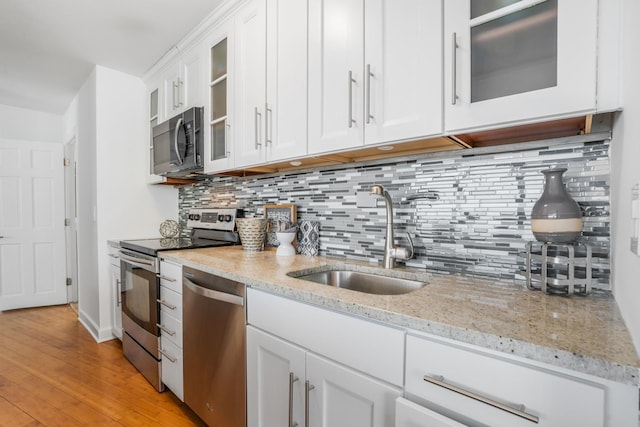 kitchen featuring white cabinetry, sink, light stone counters, and appliances with stainless steel finishes