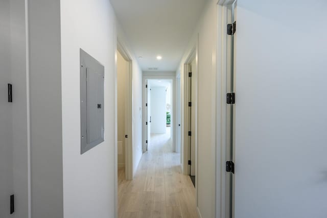 corridor with electric panel and light hardwood / wood-style flooring