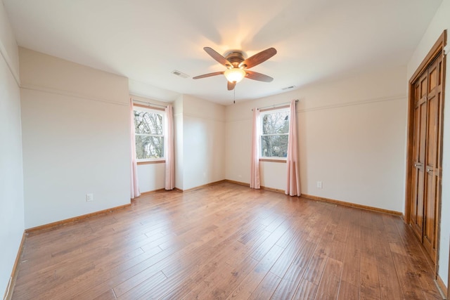 empty room with ceiling fan, a healthy amount of sunlight, and light wood-type flooring