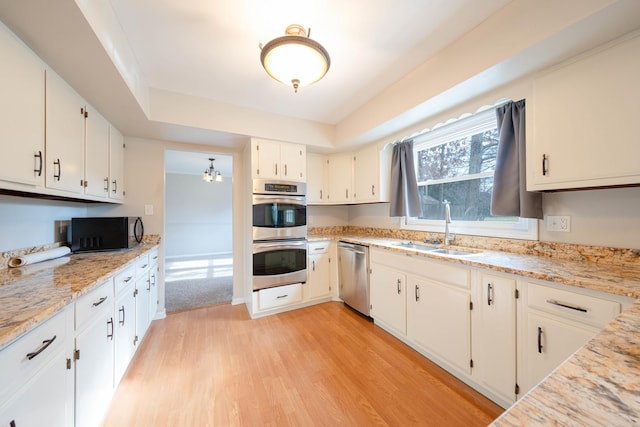 kitchen with white cabinetry, appliances with stainless steel finishes, sink, and light hardwood / wood-style floors