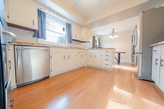 kitchen with pendant lighting, stainless steel appliances, a notable chandelier, light hardwood / wood-style floors, and white cabinets