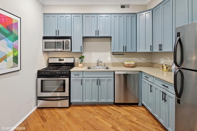 kitchen with visible vents, crown molding, light wood-style floors, stainless steel appliances, and a sink