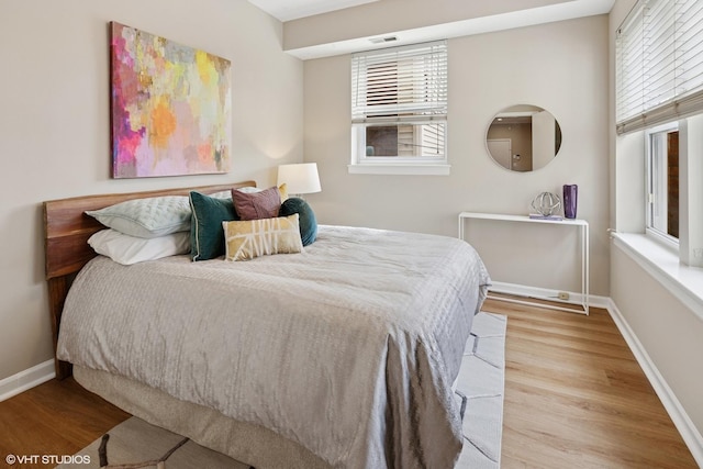 bedroom with visible vents, baseboards, and wood finished floors