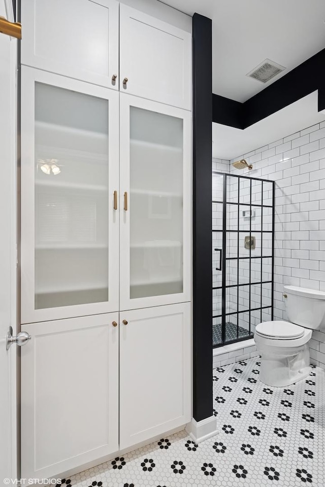 bathroom with tile patterned flooring, toilet, visible vents, and a stall shower