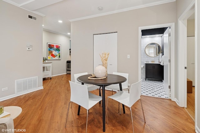 dining area featuring visible vents, light wood-style floors, and crown molding