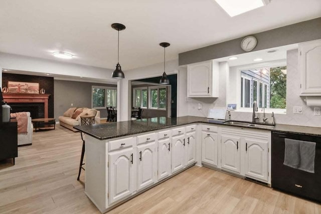 kitchen featuring sink, dishwasher, white cabinetry, decorative light fixtures, and kitchen peninsula