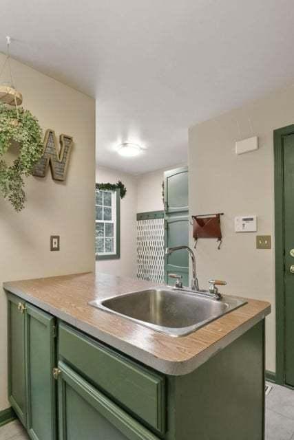 kitchen with sink, kitchen peninsula, and green cabinets