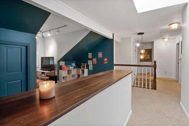 bar featuring hanging light fixtures, rail lighting, lofted ceiling with skylight, and light colored carpet