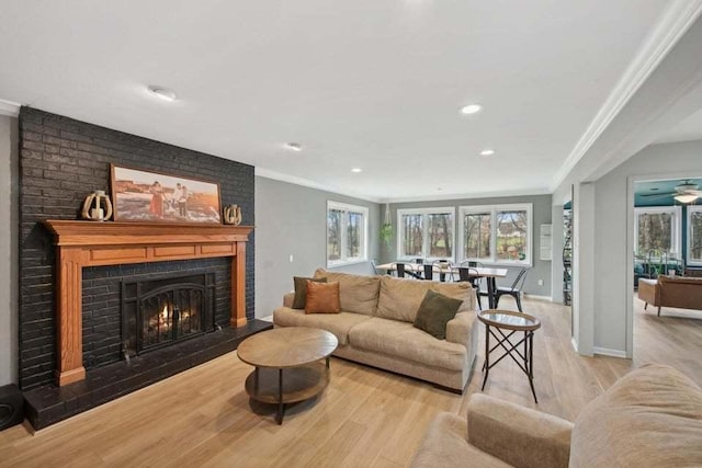 living room featuring crown molding, light hardwood / wood-style floors, and a brick fireplace