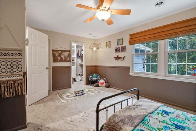 carpeted bedroom with a walk in closet, ceiling fan, and a closet