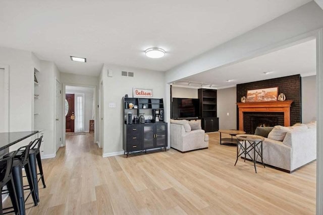 living room with a brick fireplace and light wood-type flooring