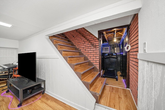 stairway featuring brick wall and hardwood / wood-style floors