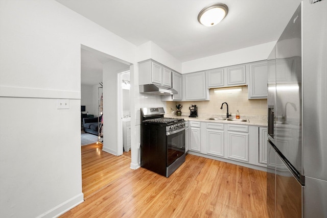 kitchen featuring stainless steel appliances, light hardwood / wood-style floors, sink, and decorative backsplash