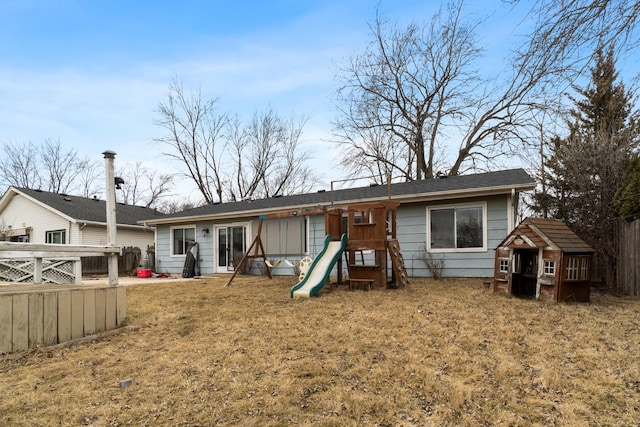 back of house featuring a lawn and a playground