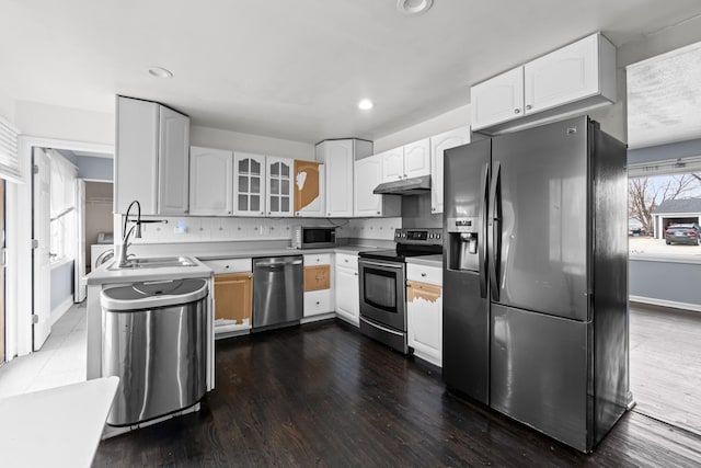 kitchen featuring sink, stainless steel appliances, white cabinets, dark hardwood / wood-style flooring, and decorative backsplash