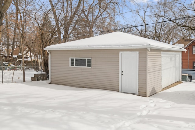 snow covered structure with fence and an outdoor structure