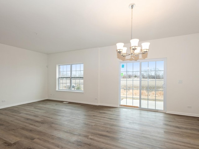 unfurnished room featuring an inviting chandelier and dark hardwood / wood-style flooring