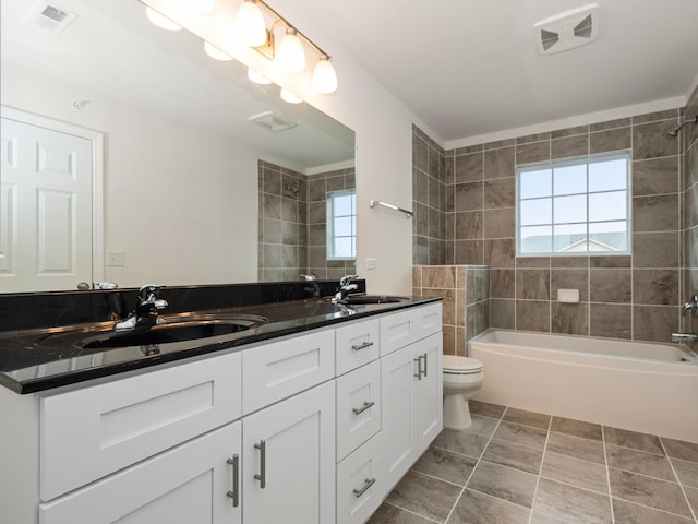 full bathroom with tiled shower / bath, plenty of natural light, toilet, and vanity