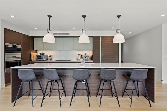 kitchen with a breakfast bar area, stainless steel appliances, and a large island with sink