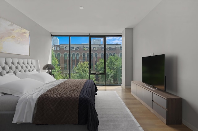 bedroom with a wall of windows and light hardwood / wood-style flooring