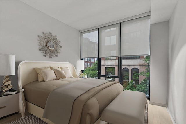 bedroom with a wall of windows and light wood-type flooring