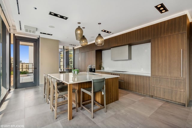 kitchen with sink, a breakfast bar, an island with sink, and hanging light fixtures