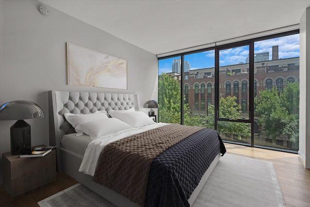 bedroom with expansive windows and hardwood / wood-style floors