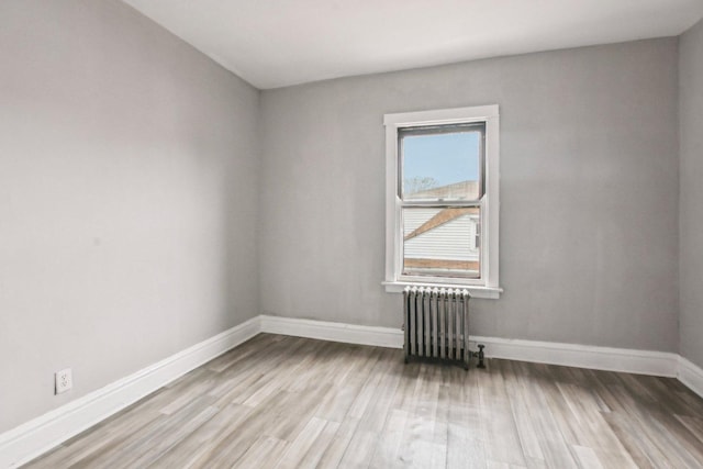 unfurnished room featuring radiator heating unit and light hardwood / wood-style floors