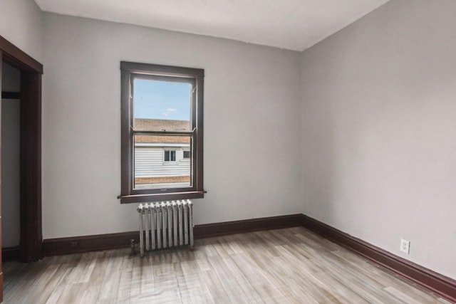 unfurnished room with radiator heating unit and light wood-type flooring