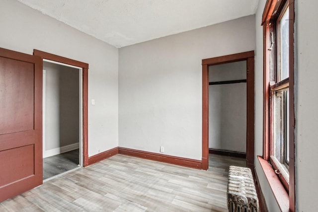 unfurnished bedroom featuring radiator and light wood-type flooring