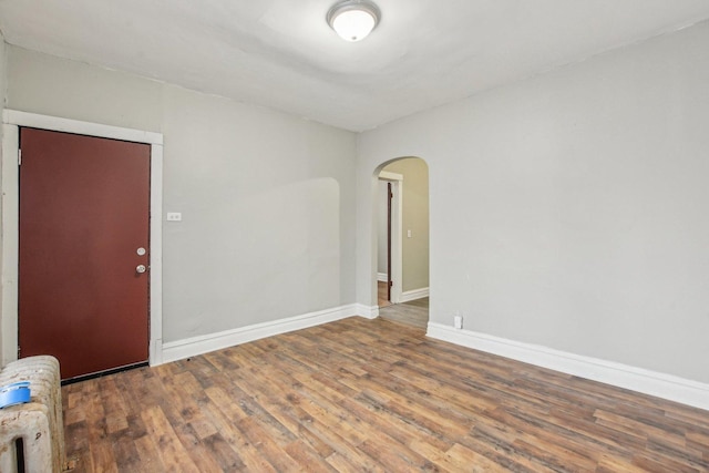 empty room with hardwood / wood-style floors and radiator heating unit