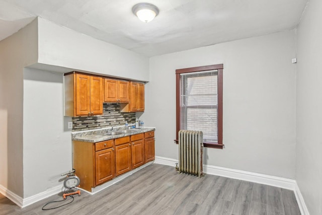 kitchen with sink, radiator heating unit, backsplash, and light wood-type flooring