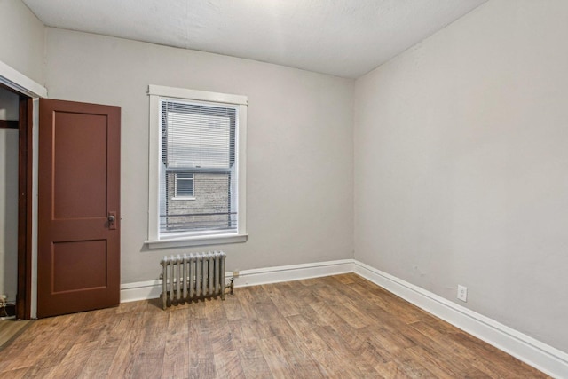 unfurnished room with radiator and hardwood / wood-style floors