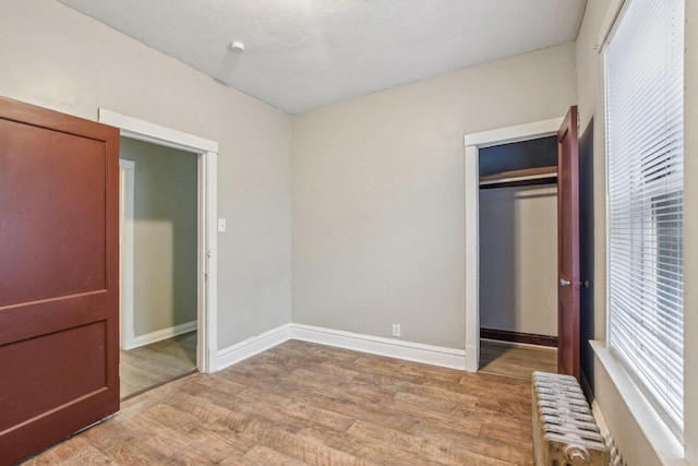 unfurnished bedroom with radiator, light hardwood / wood-style floors, and a closet