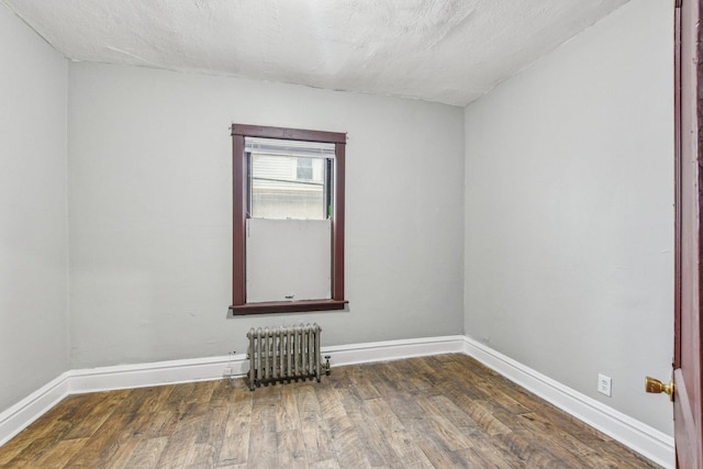 spare room with dark hardwood / wood-style flooring, radiator, and a textured ceiling