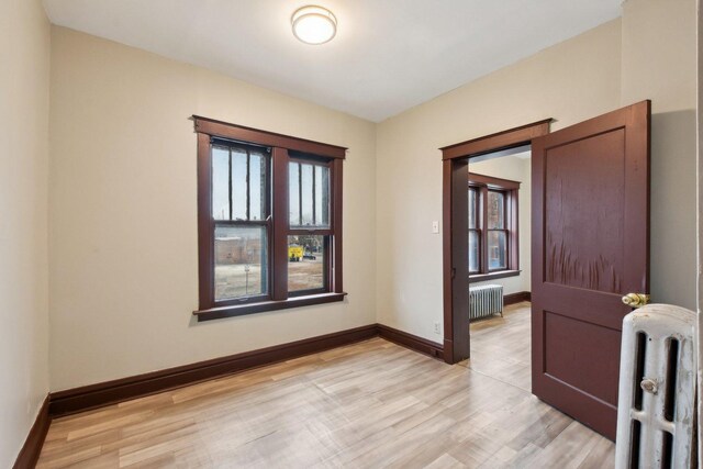 spare room featuring radiator, light hardwood / wood-style flooring, and a healthy amount of sunlight