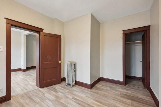 unfurnished bedroom with radiator and light wood-type flooring