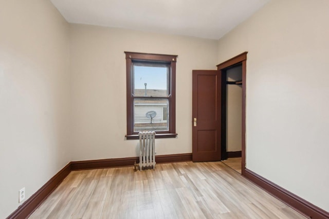 empty room with radiator heating unit and light hardwood / wood-style floors