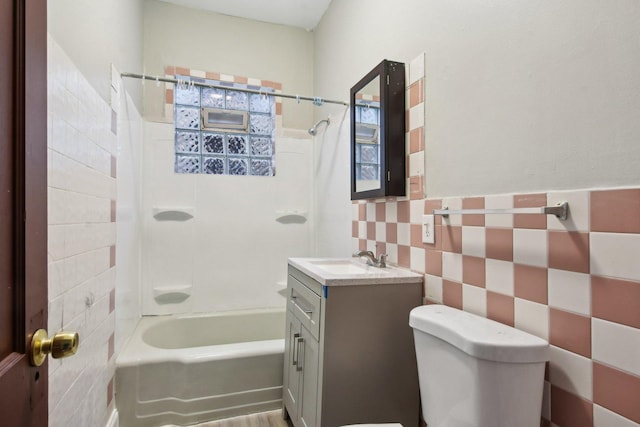 full bathroom featuring tiled shower / bath combo, vanity, tile walls, and toilet